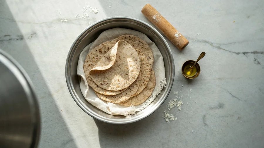 A stack of soft wholewheat rotis resting in a cloth-lined casserole, made with CressPure Sharbati atta