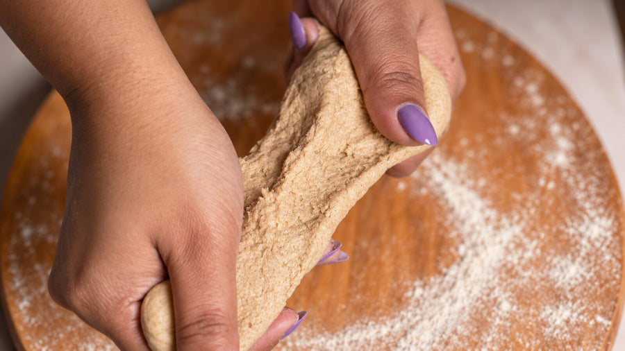 Hands stretching chakki-ground atta dough, showing the texture difference between chakki and roller mill atta